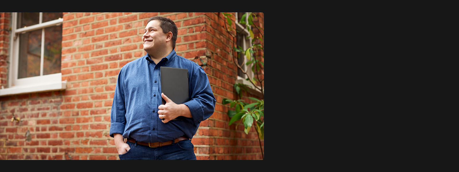 A man standing outside holding a laptop