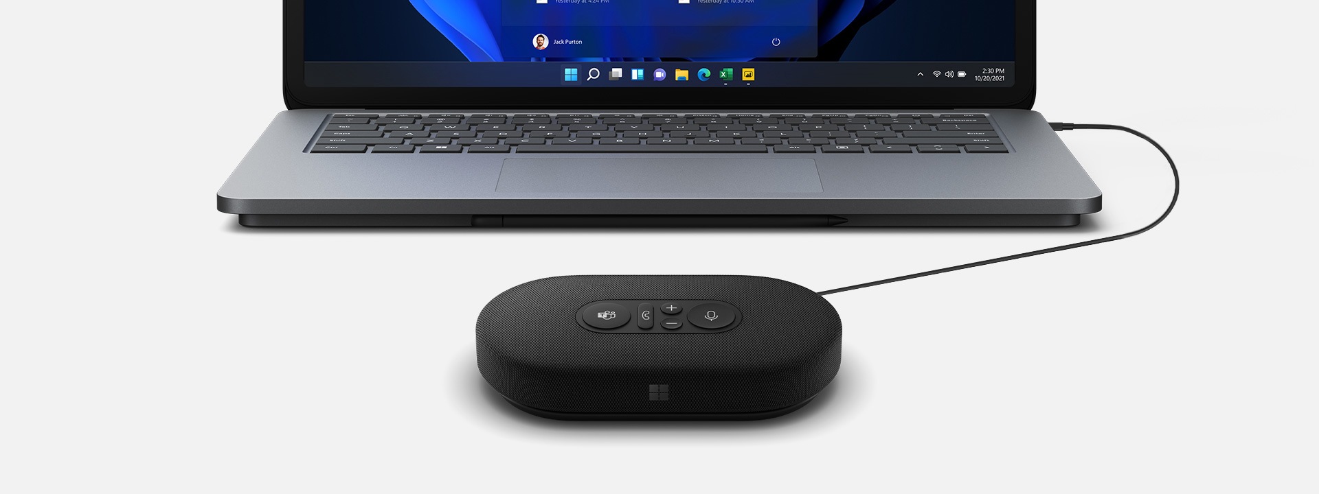 A render of a Microsoft Modern USB-C Speaker plugged into a Surface device in the background