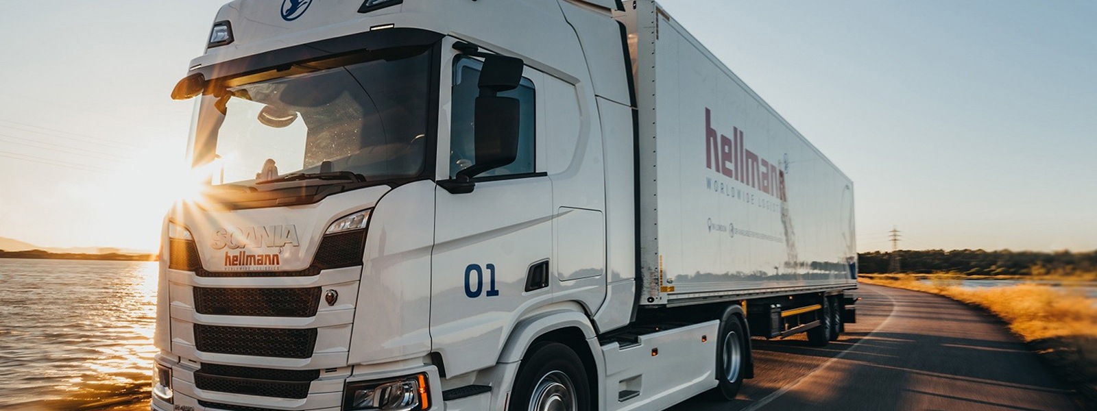 A Hellmann Worldwide Logistics truck on an open road.