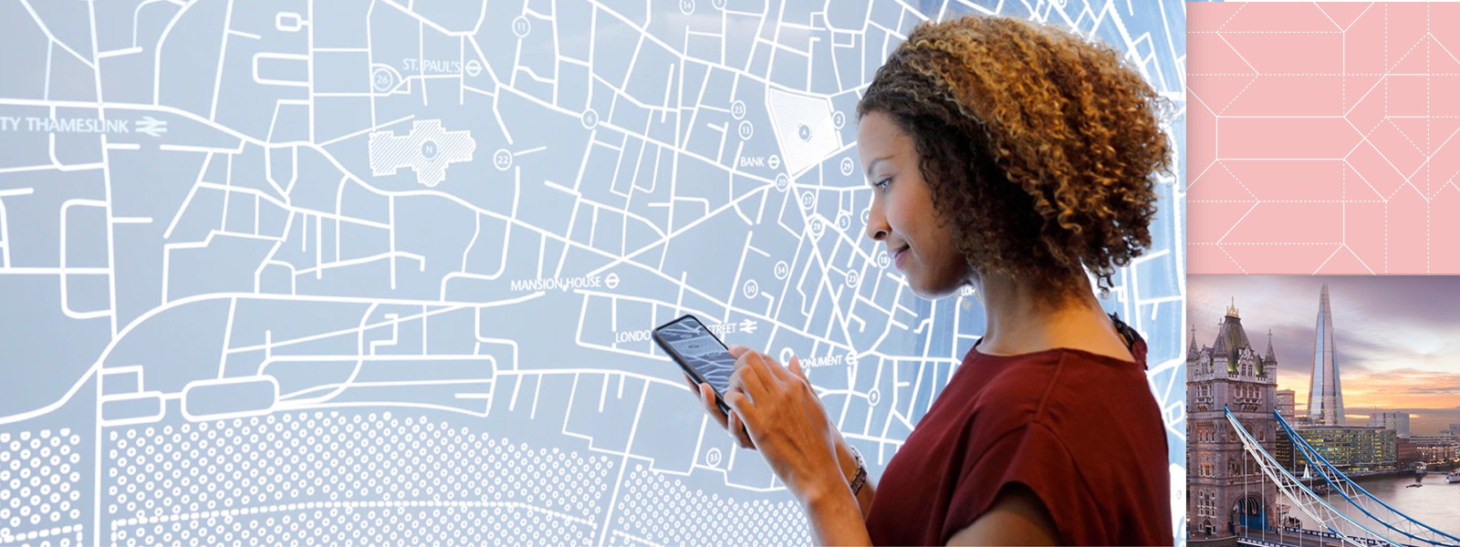 Woman uses a mobile device in front of a map display with an abstract overlay.