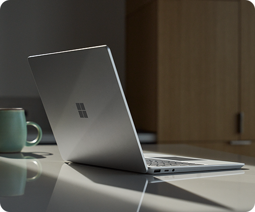 A Surface Laptop Go 2 is seen on an office desk with a drink mug nearby