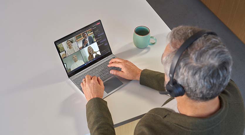 Bovenaanzicht van een persoon met Surface Headphones 2 tijdens een Teams-meeting op een Surface Laptop Go 2