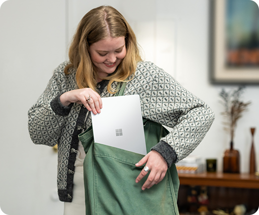 ผู้หญิงคนหนึ่งกำลังใส่ Surface Laptop Go 2 ลงในกระเป๋าทำงาน
