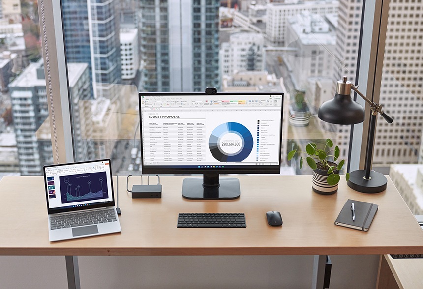 Een Surface-apparaat dat is aangesloten op een Surface Dock 2 op een bureau met een externe monitor, toetsenbord, muis, pen en notebook in de buurt