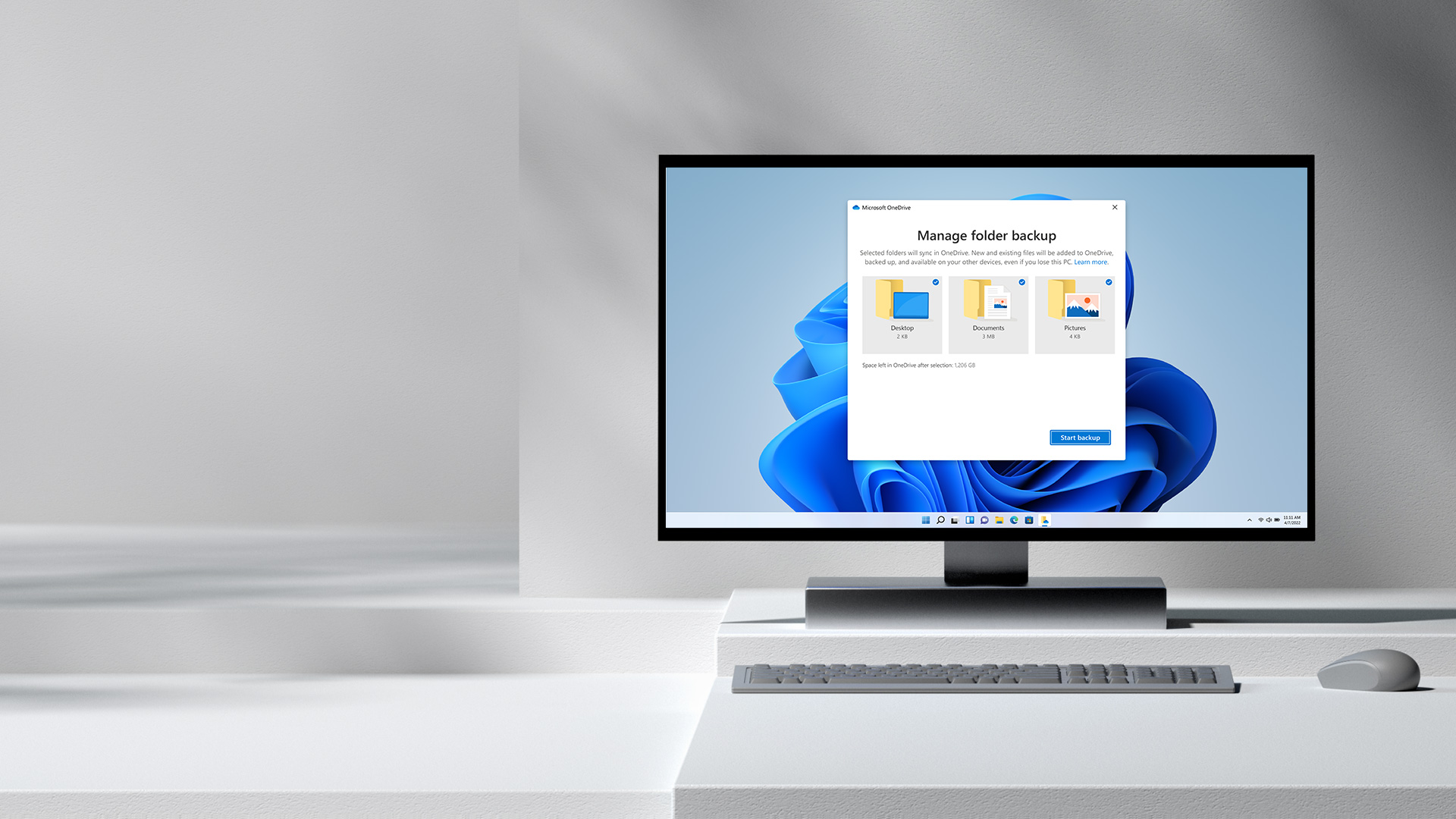 Monitor de escritorio con el cuadro de diálogo de Microsoft OneDrive, un teclado y mouse