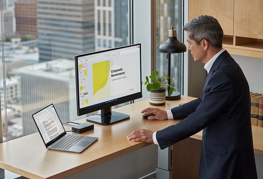 男人使用滑鼠，在連接到 Surface Laptop Go 2 的外接螢幕上瀏覽 PowerPoint 簡報
