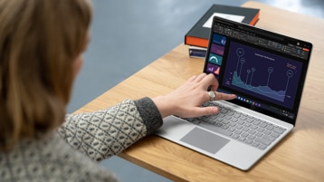 O persoană folosește ecranul tactil al unui dispozitiv Surface Laptop Go 2 pentru business.