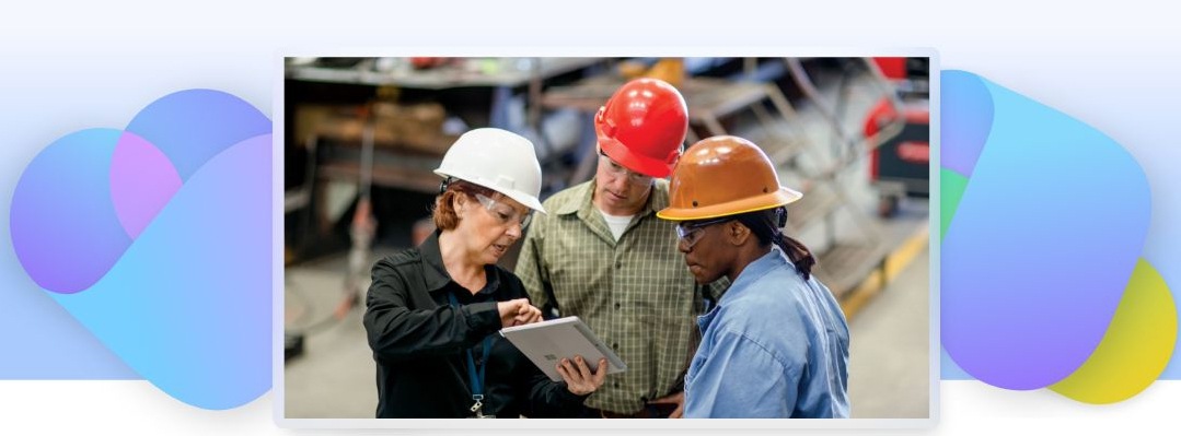 Three frontline workers wearing protective helmets looking at a tablet device.