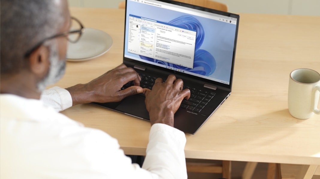 A person typing an email in Outlook on a laptop.