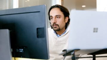 Male office worker looking at monitor on desk.
