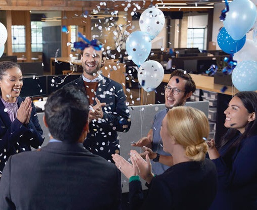 Microsoft employees celebrating an accomplishment in a gathering space in a Microsoft office.