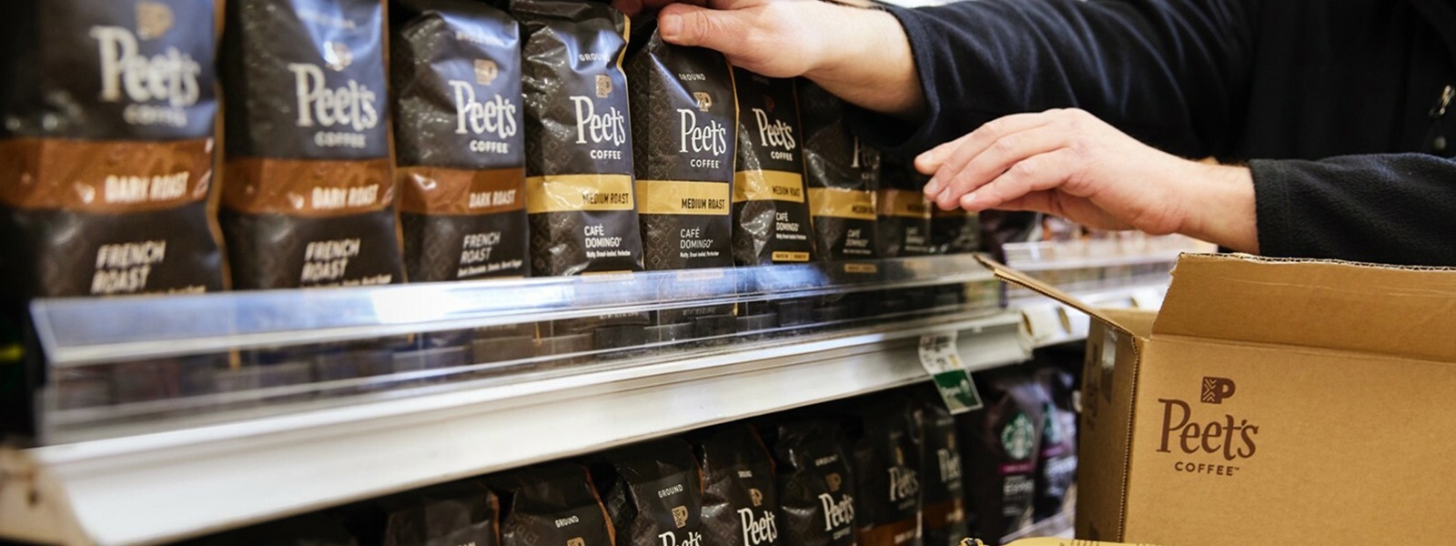 Bags of Peet's Coffee being placed on a grocery store shelf