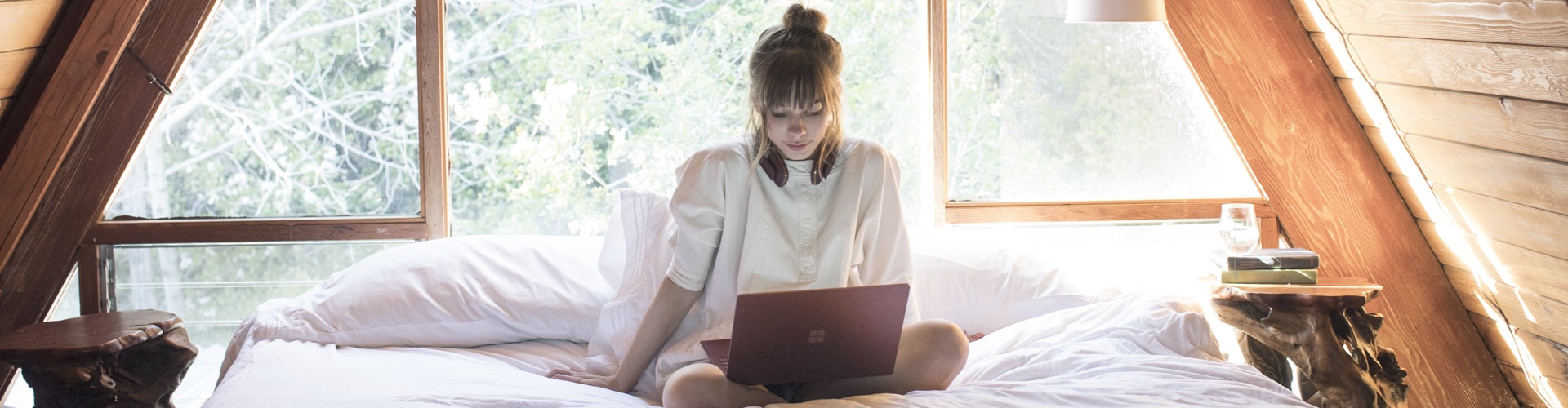 Person sitting on their bed working on a Surface laptop