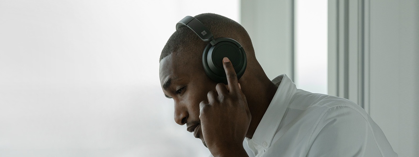 A man wears the black Headphones 2 while touching the left dial