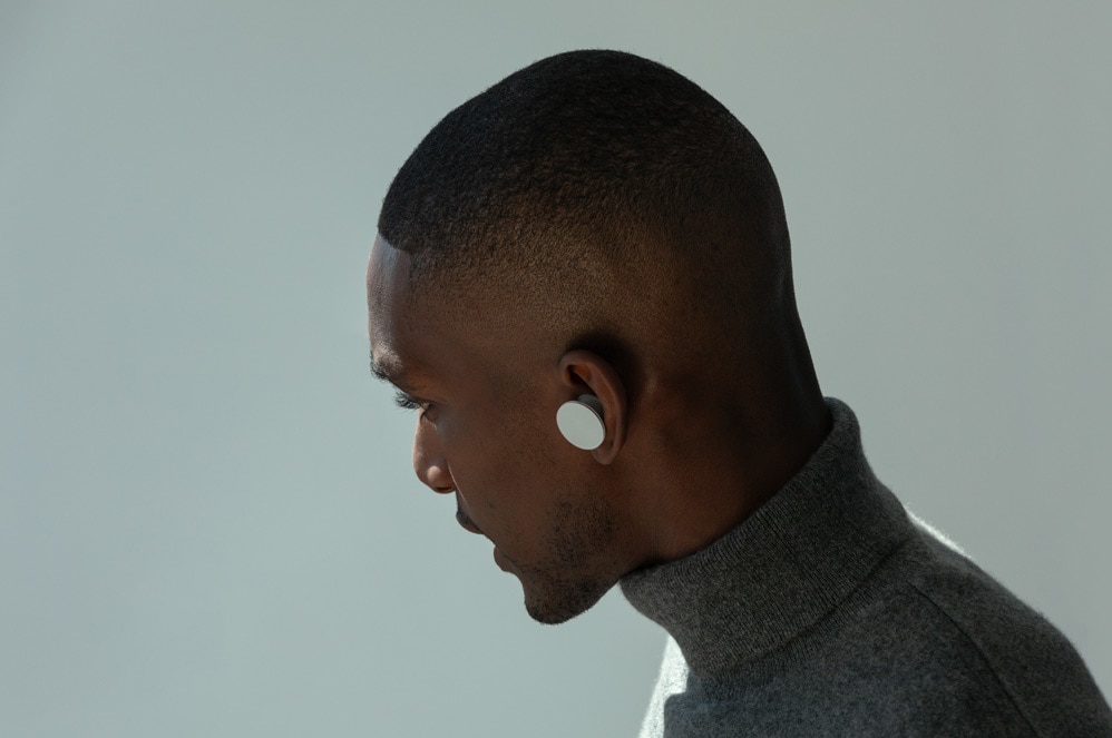 A man wears Surface Earbuds while answering a phone call.