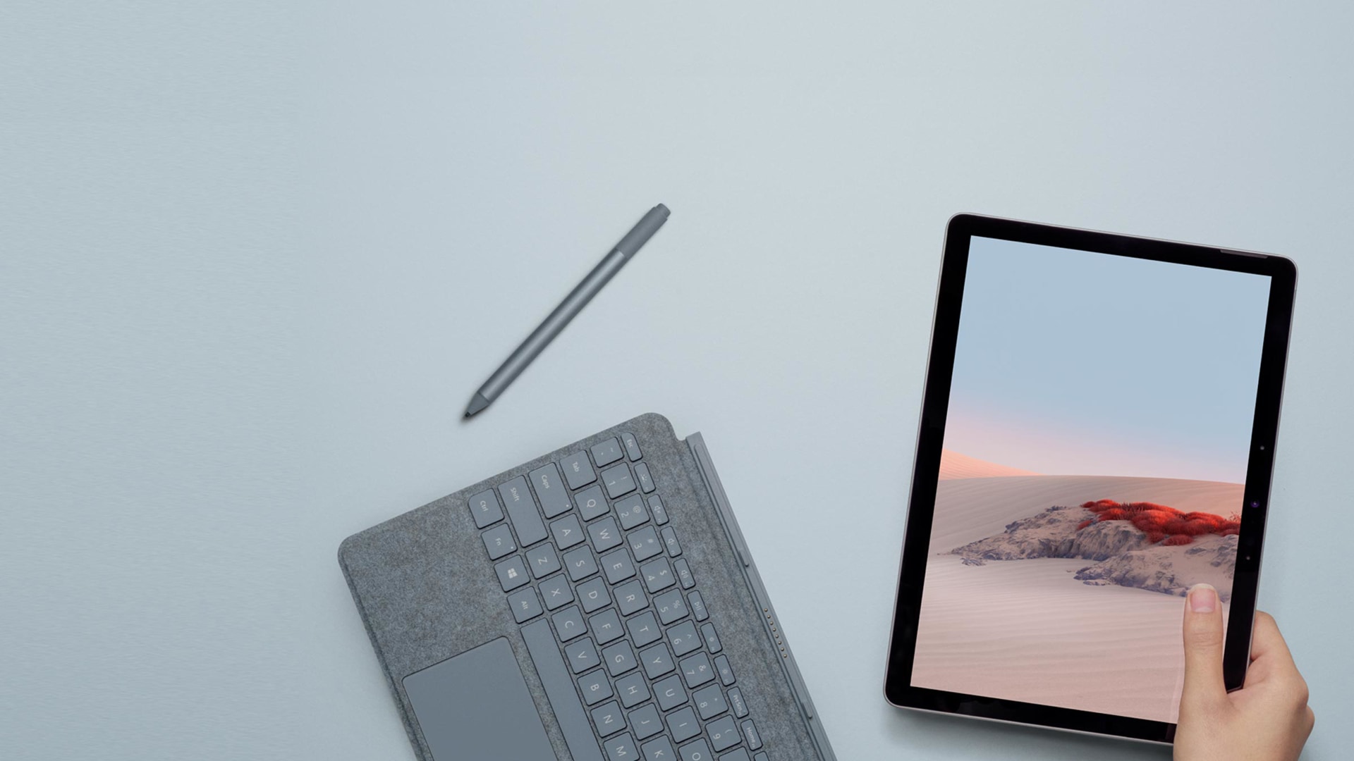 Surface Go 2 in de hand van een vrouw naast een Type Cover en Surface Pen