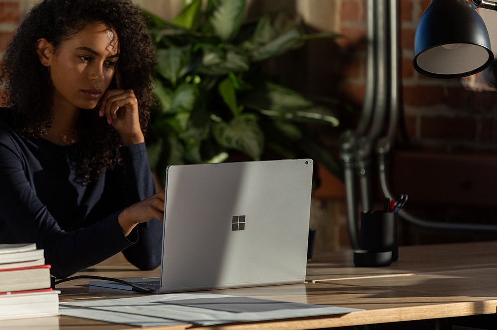 A woman working on a Surface Book 3 in an open office