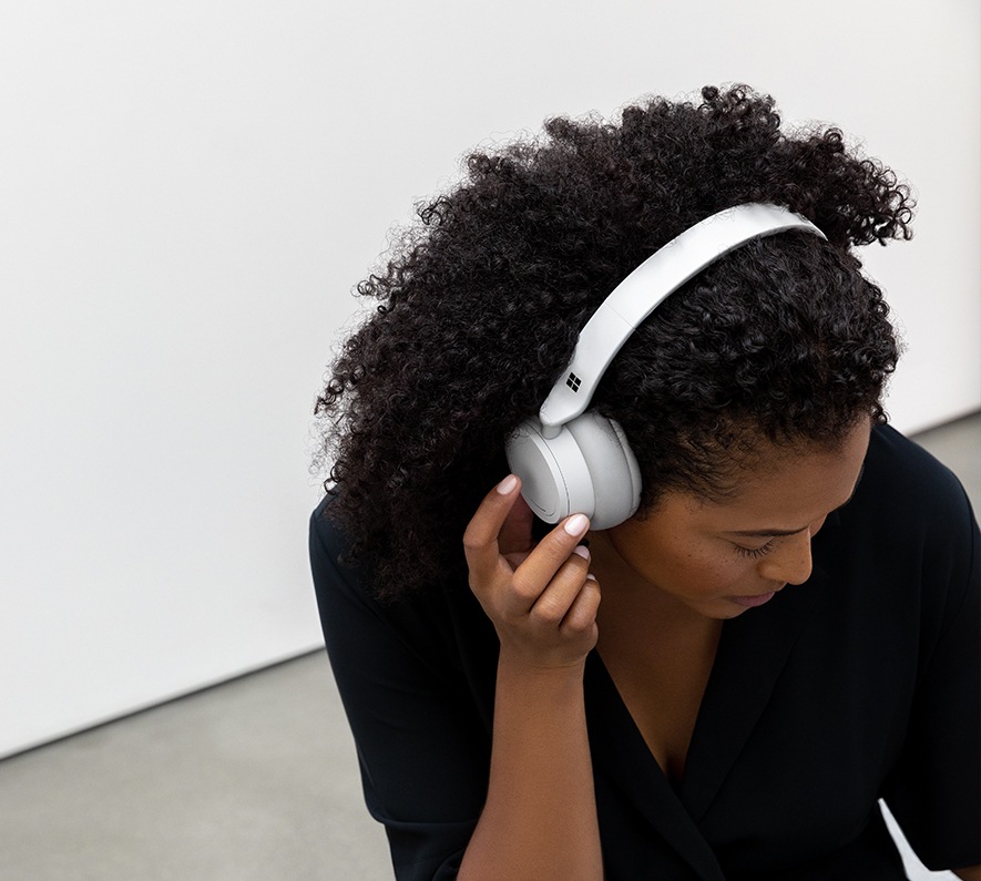Woman wearing Surface Headphones with her hand on the side of the headphones 
