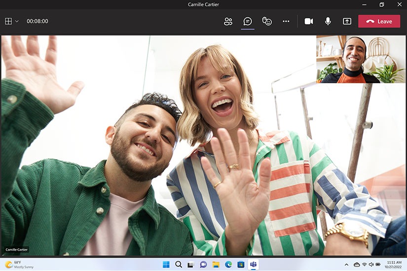 Friends use Microsoft Teams to stay in touch. They are seen smiling and waving at each other.