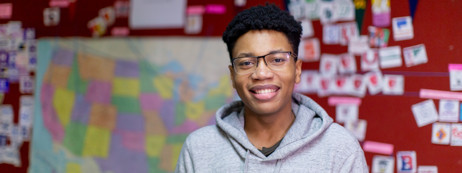 A smiling high school student standing in a classroom.