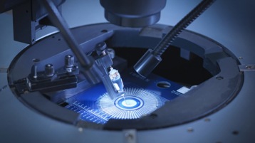 Screenshot aus dem Video, der eine Maschine zeigt, die ein elektronisches Bauteil fertigt.
