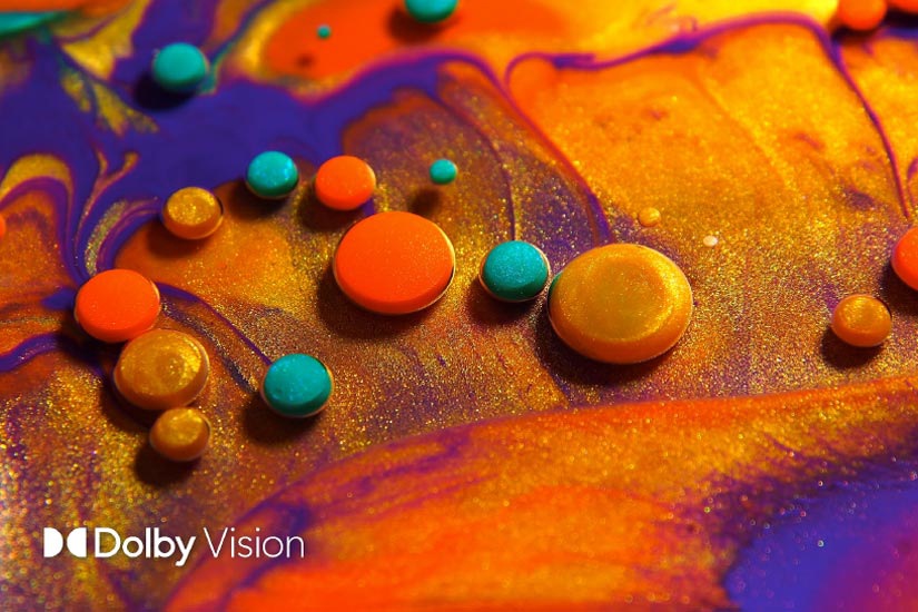Red, gold and aqua paint drops float on the surface of swirling sand in colors of gold, purple and red.