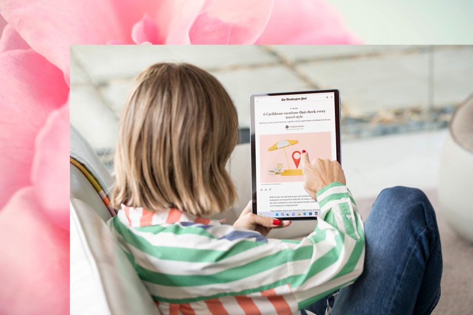 Una donna seduta su un divano utilizza un dispositivo Surface Pro 9 per leggere le notizie.