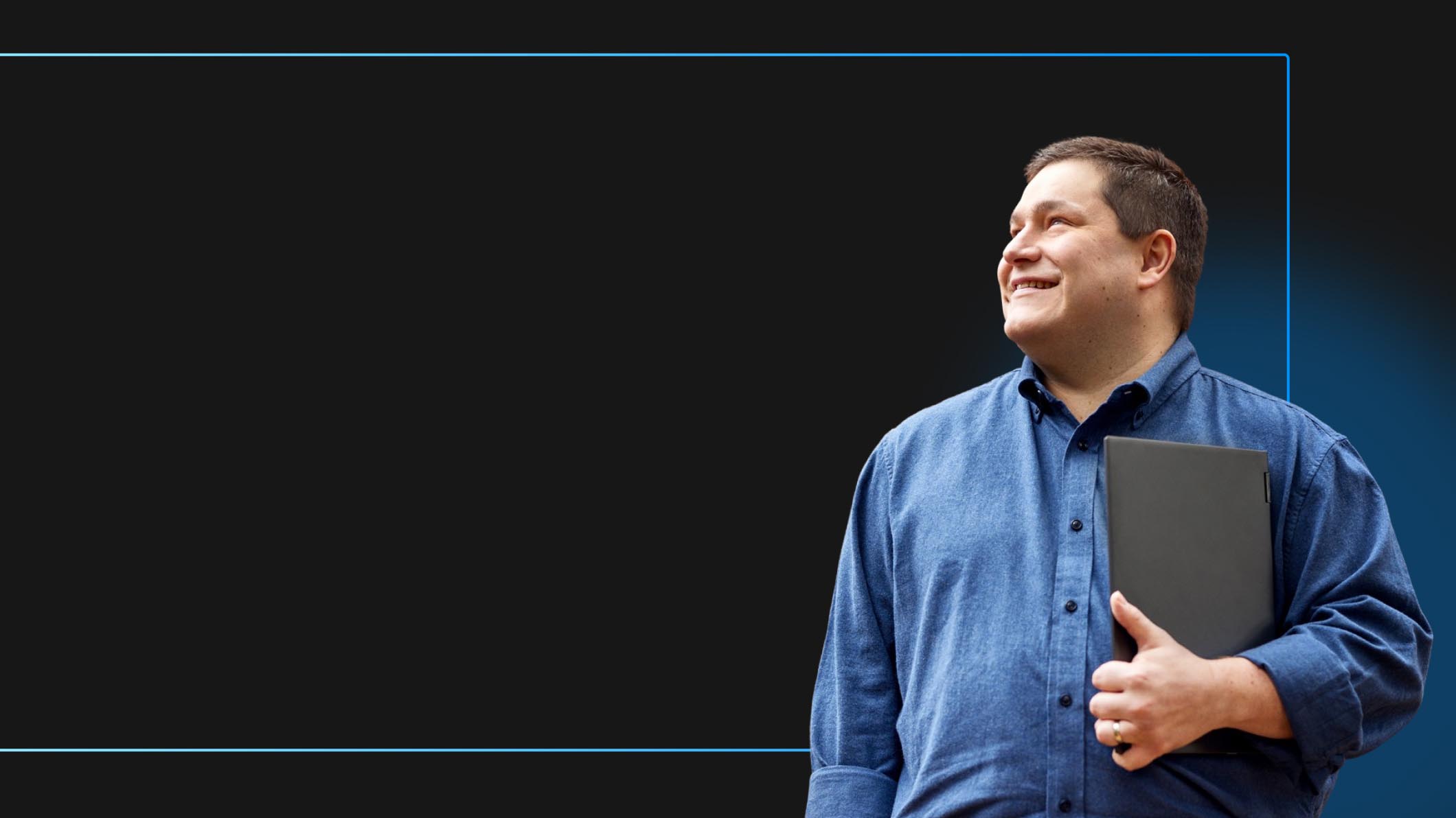 Sr. Cloud Security Consultant Alan Armstrong looks off smiling and holding a Windows device
