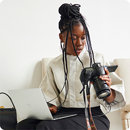 Person with long braids holding a PC and camera