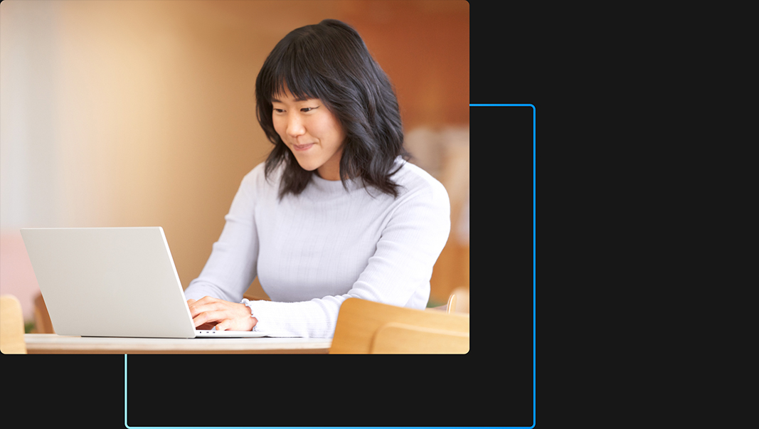 Een persoon die glimlacht terwijl hij of zij op zijn laptop werkt in een kantooromgeving