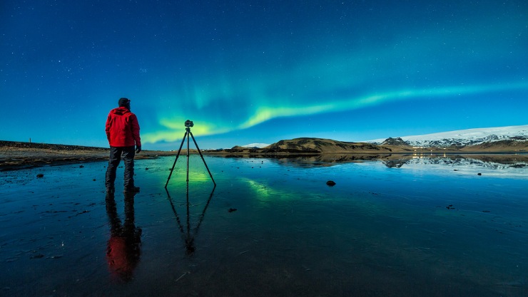 Silhouette of a man filming the northern lights.