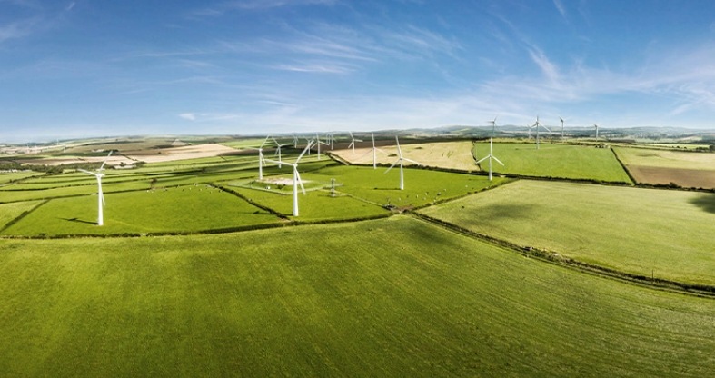 Einige grüne Felder von oben mit mehreren Windkrafträdern.