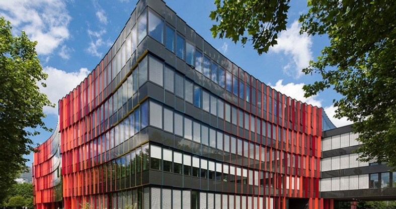 Modernes Gebäude mit Glaswänden und roten Akzenten. 