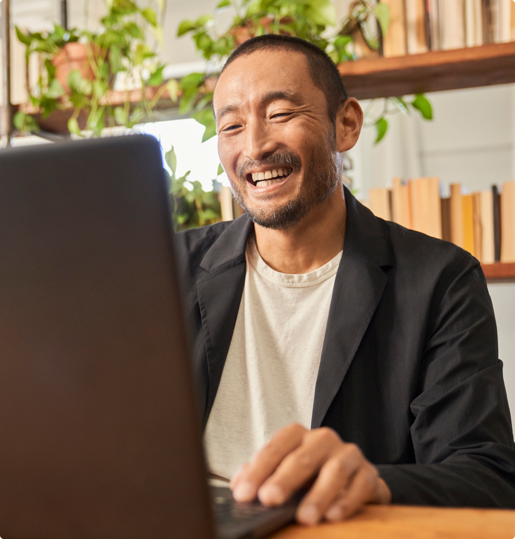 Άνδρας που χαμογελά και κοιτάζει τον υπολογιστή του