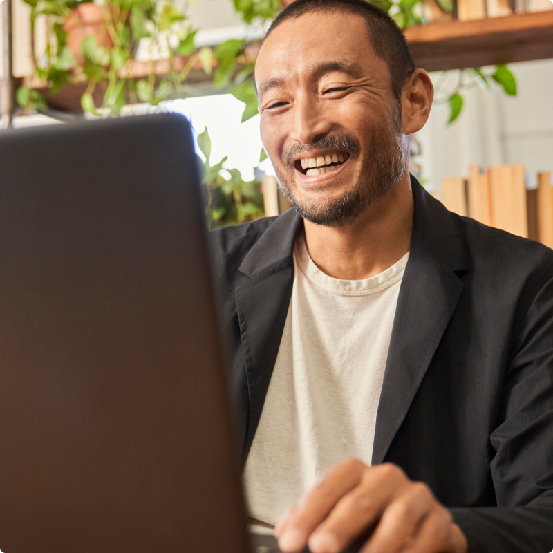 Άνδρας που χαμογελά και κοιτάζει τον υπολογιστή του