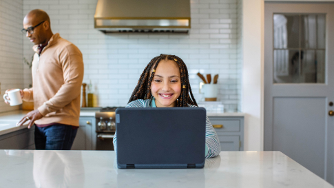 Mladé dievča v kuchyni používa prenosný počítač