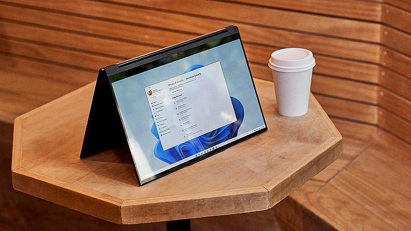 מחשב נייד מונח על שולחן עם כוס קפה לידו