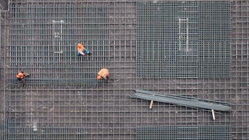 Aerial view of construction workers working on a steel grid foundation.