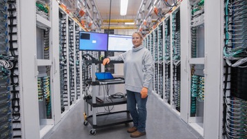 Close up image of female datacenter employee in cold aisle smiling.