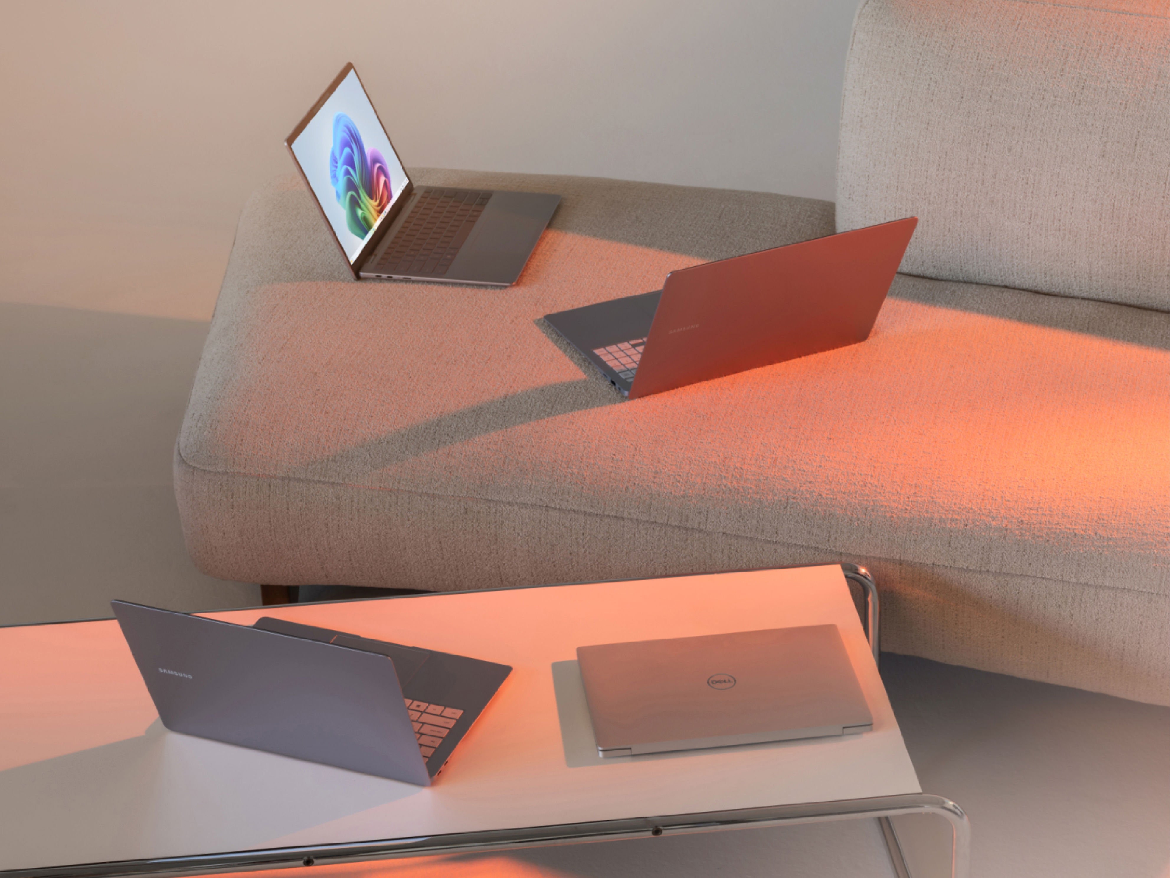 Multiple laptops sitting on a coffee table and sofa