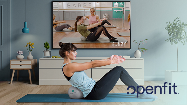 Woman in a live work out session performing abdominal crunches from her living room, which includes a TV, sideboard, table, and plants