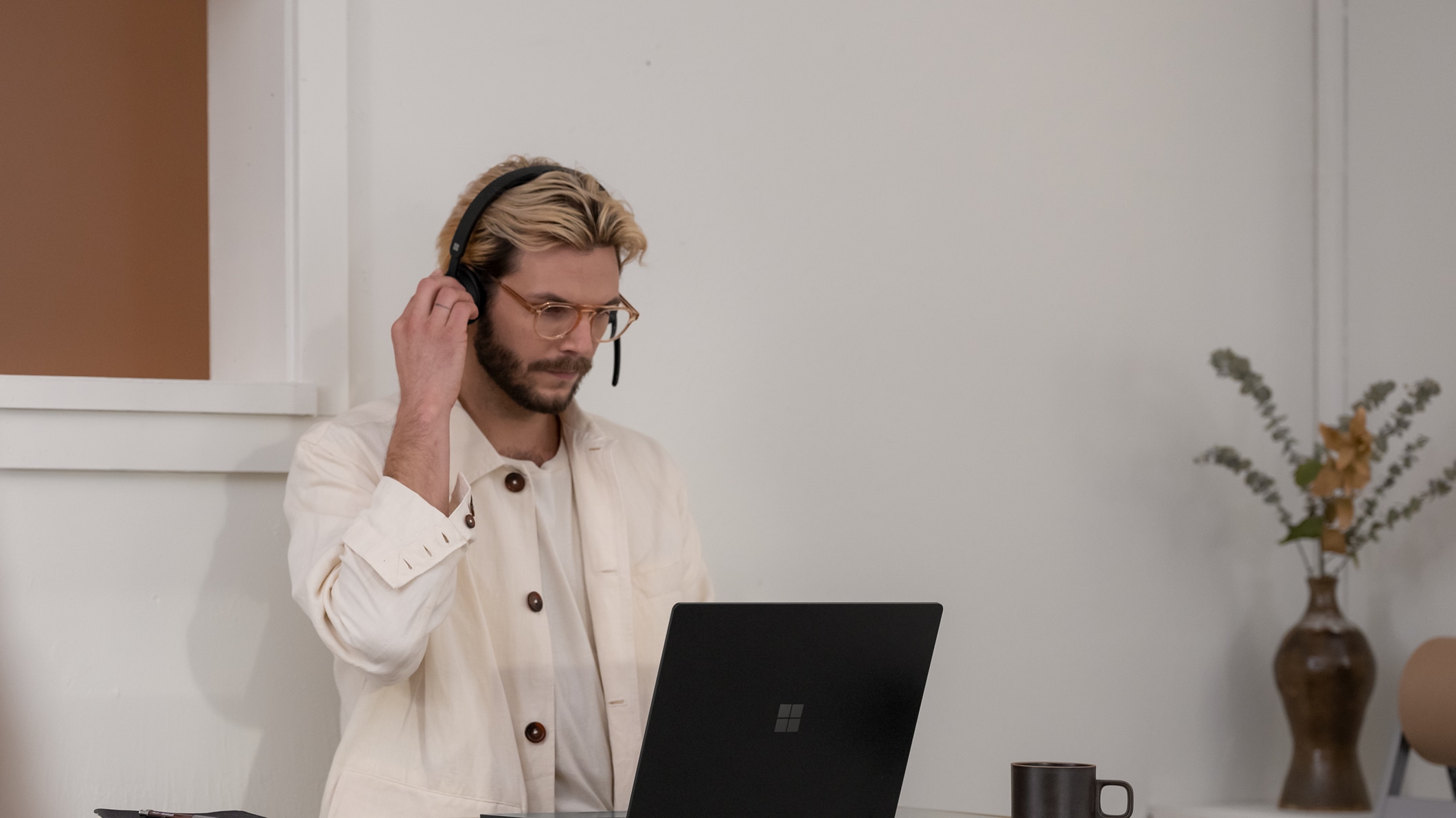 A person uses a Microsoft Modern Wireless Headset while looking at a device.