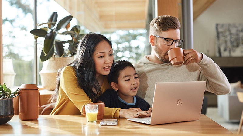 A family of three looking at a Surface laptop together.