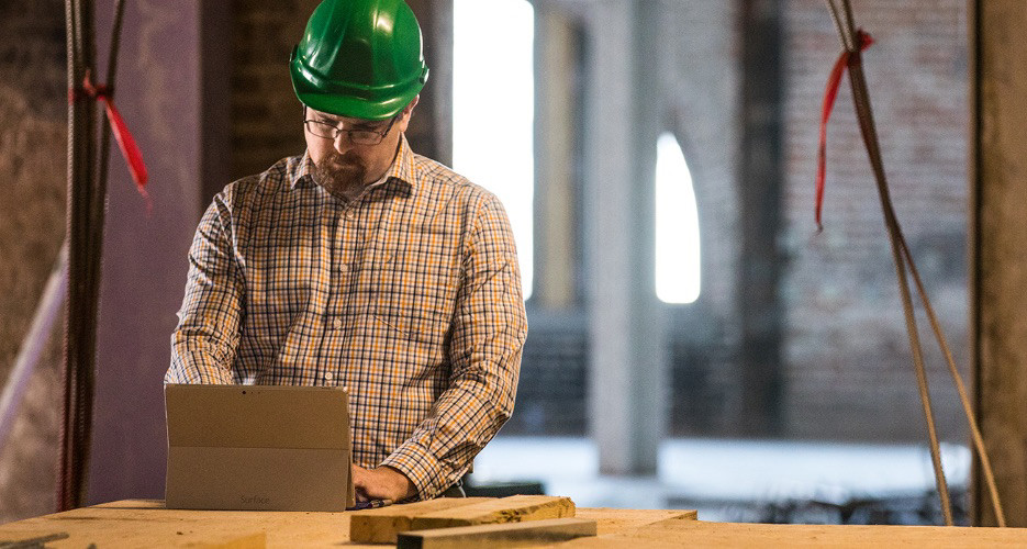 A person wearing a hard hat and using a tablet.
