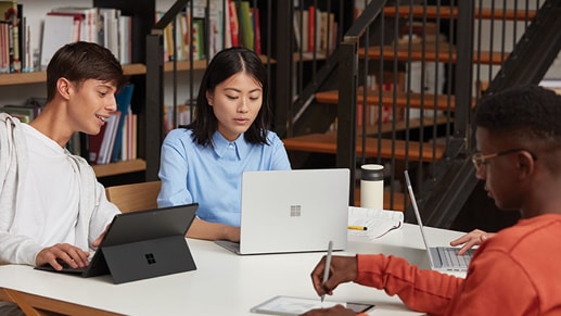 Four teens working on Surface devices in a library.