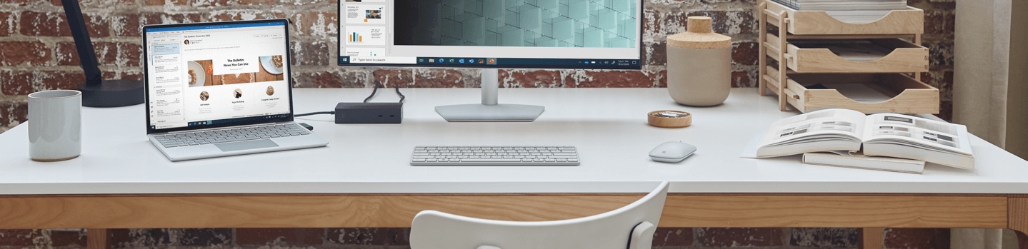 Un escritorio con una tableta, un monitor de escritorio, un teclado, libros y otros objetos