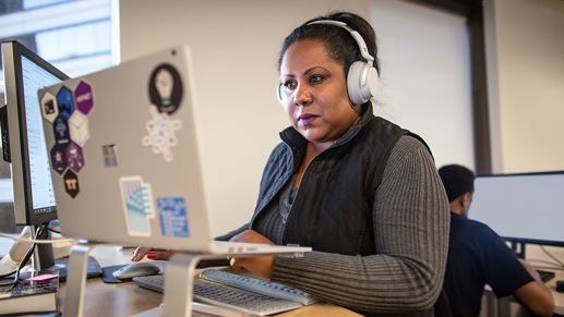 A person sitting in an office working at their desk with headphones on.