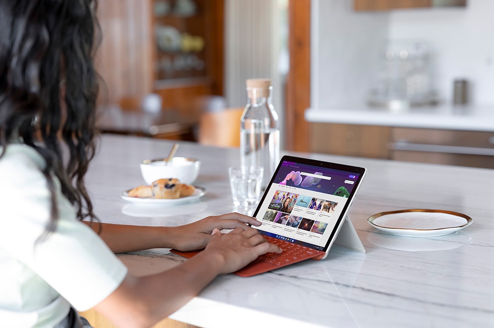เด็กคนหนึ่งกำลังใช้ Surface Go 3 เป็นแล็ปท็อปที่เคาน์เตอร์ในห้องครัว