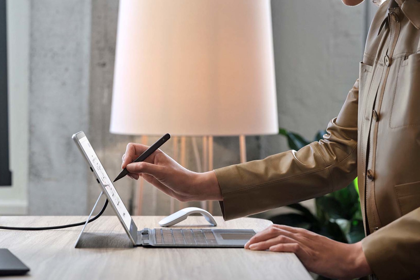 站在桌边正使用 Surface 超薄触控笔 2 在 Surface Pro X 设备上书写的人