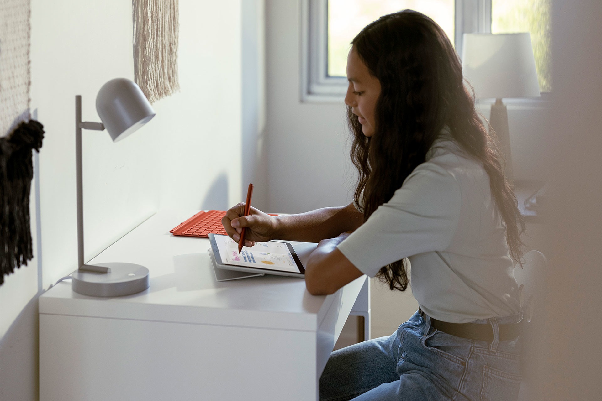 Seorang anak menggunakan Surface Go 3 dan Pen Surface untuk mengambil nota kelas.